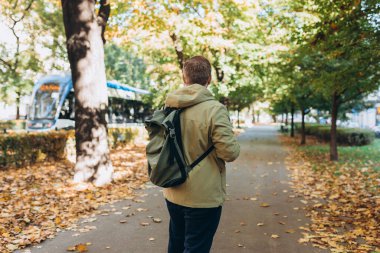 Sonbahar Park Caddesi 'nde sırt çantası takan sarışın genç adam. Şehir yaşam tarzı konsepti. Yüksek kalite fotoğraf