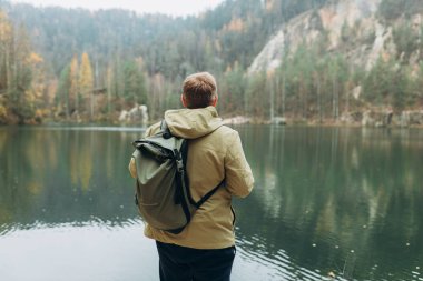30 'lu yaşlarda sırt çantalı sarışın bir gezgin görkemli gölün güzel manzarasının tadını çıkarıyor. Seyahat, macera. Etkin bir yaşam biçimi kavramı.