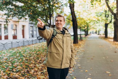 Sonbahar Park Caddesi 'nde sırt çantası takan sarışın genç adam. Şehir yaşam tarzı konsepti. Yüksek kalite fotoğraf