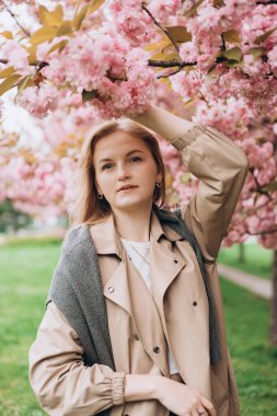 Genç, güzel, gülümseyen, 30 'lu yaşlarda, moda elbiseli, botanik bahçesinde duran bir hippi. Çiçek açan ağaçlarda poz veren kaygısız kadın. Çiçek açan bahçede bir kız. Kadınlar için bayrak