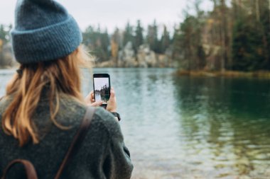 Şapkalı kişi, vahşi doğa arka planında göl kenarında akıllı bir telefonla içeriği kaydediyor. Dışarıda telefonla dolaşan 30 'lu yaşlarda şık bir kız. Seyahat, macera. Etkin bir yaşam biçimi kavramı