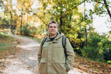 Sonbahar Park Caddesi 'nde sırt çantası takan sarışın genç adam. Şehir yaşam tarzı konsepti. Yüksek kalite fotoğraf