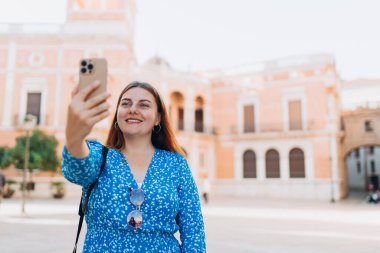 Mutlu 30 'lu yılların kadınları kentin arka planında selfie çekiyor. Valencia Katedrali 'ni ziyaret eden bir gezgin. İspanya 'da yaz tatilleri. Dişi, şehri keşfediyor. En iyi turistik yer..
