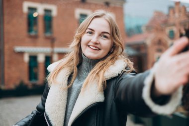 Güzel bir kadın kameraya bakar ve sokakta selfie çeker. Blogculuk, teknoloji, yaşam tarzı, seyahat, turizm, aktif yaşam.