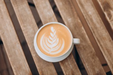 Cup of coffee on the wooden table with latte art. Street coffee, top view.
