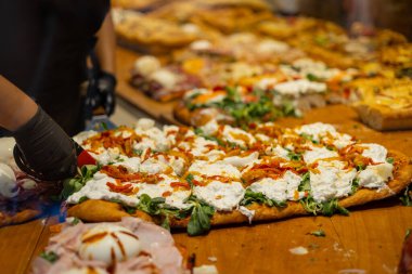 Sicilya usulü dikdörtgen peynirli ve domatesli pizzadan bir dilim servis ediyorum. İtalya 'da bir restoranın vitrininde otantik İtalyan pizzası.