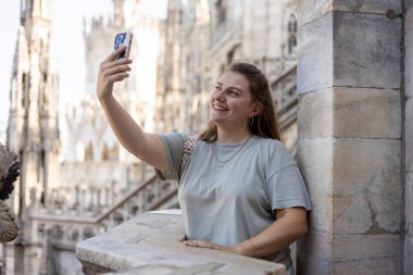 Milan Katedrali 'nin çatısında selfie çeken güzel bir kadın Duomo di Milano, İtalya. Yazın Avrupa 'yı geziyorum. Çekici kadın şehri keşfediyor, turist akıllı telefondan fotoğraf ya da video çekiyor