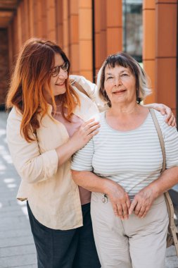 Yetişkin kızı dışarıda poz veren kıdemli kadın..