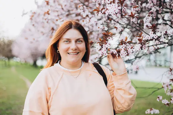 Kiraz çiçekli bir kadının portresi. Bedava açık hava eğlencesi, bahar çiçekli bahçe..