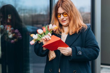 Güzel, güzel, güzel, neşeli bir kadının portresi tebrik kartı alıyor. Kutlamalar ve büyük buket çiçekler, açık havada..