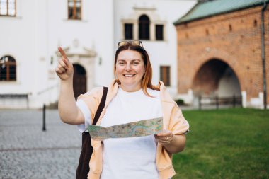 Neşeli kadın arama yönünü yere harita yaz, mutlu kadın turist hotel atlas tatil sırasında yabancı bir şehirde arama yolu yurt dışında seyahat ederken