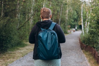 Yazın ormanda yürüyüş yapan beyaz bir erkek var. Seyahat, aktif yaşam tarzı, insanlar ve hobi konsepti. Açık havada duran spor elbiseli sarışın erkek. Gezgin eko-turizmin, dikiz aynasının tadını çıkarıyor