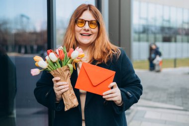 Güzel, güzel, güzel, neşeli bir kadının portresi tebrik kartı alıyor. Kutlamalar ve büyük buket çiçekler, açık havada..