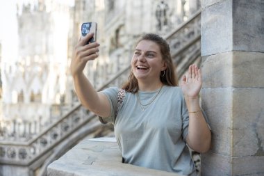 Milan Katedrali 'nin çatısında selfie çeken güzel bir kadın Duomo di Milano, İtalya. Yazın Avrupa 'yı geziyorum. Çekici kadın şehri keşfediyor, turist akıllı telefondan fotoğraf ya da video çekiyor
