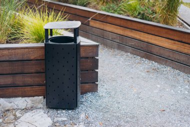 Siyah modern çöp kutusu parkta.