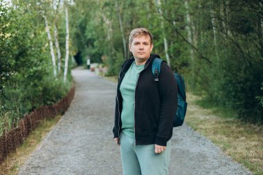 Sırt çantalı mutlu genç adam yeşil şehir parkında doğa üzerinde yürüyor. Yaşam tarzı eğlence konsepti. Yüksek kalite fotoğraf.