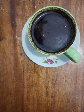 Bir fincan sade kahve, ahşap bir masada fotokopi alanı olan..