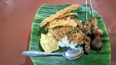 Endonezya Geleneksel Gıda Nasi Pecel ve Yeşil Muz Yaprağı 'nda servis edilen Tavuk Salatası Satay. Fıstık soslu, pilavlı ve sebzeli Doğu Java mutfağı. Otantik Asya Tabağı