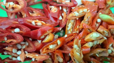 Dilimlenmiş kırmızı biber, yüksek çözünürlüklü yeşil arka planda izole edilmiş kırmızı biber fotoğrafı, yemek tarifleri, baharatlı mutfak, arka plan ve mutfak tasarımı için ideal.