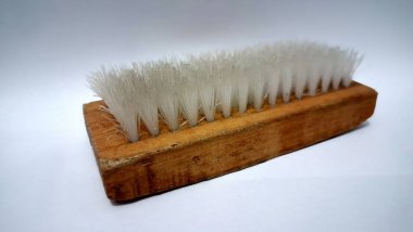 Düz beyaz bir yüzeyde izole edilmiş dayanıklı beyaz tüyleri olan sıkıştırılmış ahşap temizlik fırçası, çeşitli temizlik ve bakım ihtiyaçları için uygundur (insan yok).