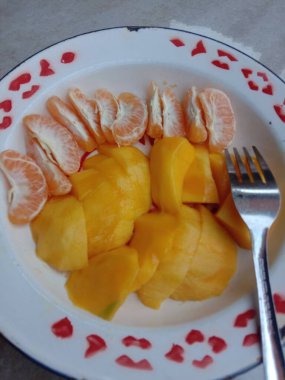 Bir tabakta portakal ve mango. lezzetli taze portakal meyvesi