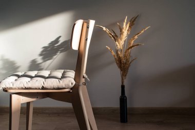 Kurumuş çiçeklerle dolu, batan güneşin ışınlarında yastıklı, basit, açık ahşap bir sandalye.