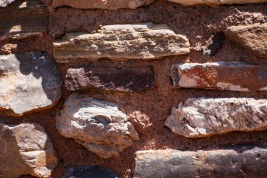 Çeşitli kaba taşlar ve betondan oluşan duvar dokusunun yakın görüntüsü. Soyut taş yüzey arkaplanı.