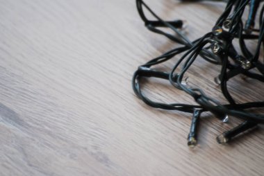 Ahşap arka planda ampulleri olan yeni yıl çelenkleri. Parıldamıyor. Yeşil kablo