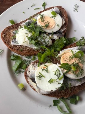 Geleneksel Letonya mutfağı aperatifi olan tuzlanmış spat sandviçi, tereyağı, haşlanmış yumurta, taze soğan ve bir dilim çavdar ekmeği üzerine otlar servis edildi.