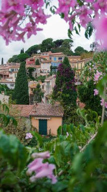 Bormes-les-Mimosas Ortaçağ köyünün panoramik manzarası Pembe trompet asması veya Podranea ricasoliana çiçekleri çerçeveli, Var, Fransa 'nın Provence kentinde