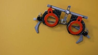 Optimetri kavramı. Lens setindeki düzeltici lenslerle deneme çerçevesi. Gözlük için vizyon sınavı. Sarı arkaplan