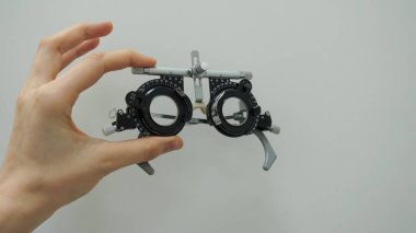 Optimetri kavramı. Lens setindeki düzeltici lenslerle el ele tutuşan deneme çerçevesi. Gözlükler için görüş sınavı