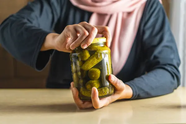 Bir kadın tüm gücüyle turşu kavanozunu açmaya çalışır.