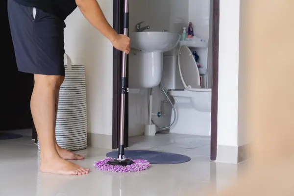 Bir mafyayla apartman zeminini temizleyen kişi.