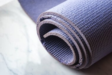 Yoga minderi mermer tezgahın üzerine sarılmış. Paspas mor ve biraz yıpranmış.