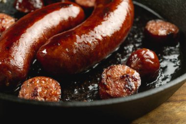 cured red juicy smoke beef sausage sear on cast iron skillet  clipart