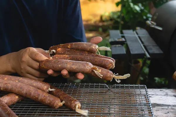 stock image A man is holding homemade sausages that use collagen casings and have been cured, they will be cooked using the cold smoking technique
