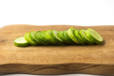 Ahşap kesim tahtasındaki salatalık dilimi, beyaz arka planda izole.