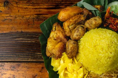 Nasi kuning veya nasi tumpeng, buharda pilav zerdeçal, kızarmış tavuk, tempeh, sambal ve taze sebzeler muz yapraklarının üstünde.