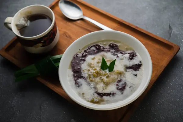 Mung fasulyesi lapası 'bubur kacang hijau' siyah glutinous tatlı pirinç, hindistan cevizi sütü ve pandan yapraklarıyla servis edilir.