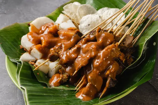 stock image sate padang, indonesian cuisine padang beef, intestine satay with spicy peanut sauce and rice cake
