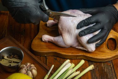 butterflying chicken, chef using scissor for removing the backbone of the chicken so it can be spread out flat, resembling the shape of a butterfly clipart