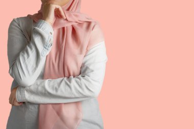 Düşünceli Müslüman kadın, elleri çenesinde, günlük kıyafetleri ve şeftali başörtüsü ya da başörtüsüyle yukarı bakıyor, pembe arka plan, iş kadını konsepti