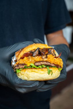 Bir şef mantar soslu çizburger yapıyor ya da hazırlıyor.