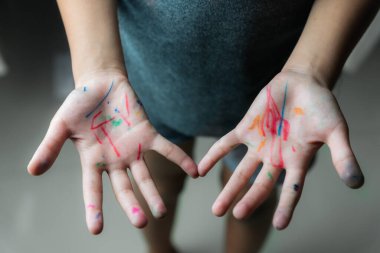 Yaratıcılık ve etkinlik kavramını temsil eden renkli kalemlerle lekelenmiş küçük bir çocuğun elleri