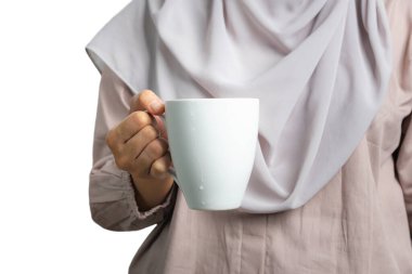 Beyaz bir kupa tutan Müslüman kadın, beyaz arka planda izole edilmiş.