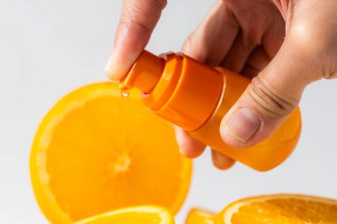 Arkaplanda taze Citrus dilimleri olan portakal vitamini damlası şişesi.