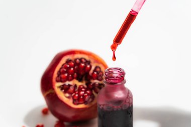 Cam damlacık şişesinde beyaz arka planda izole edilmiş, bir pipetle nar özü.