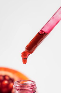 Cam damlacık şişesinde beyaz arka planda izole edilmiş, bir pipetle nar özü.