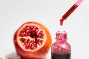 Cam damlacık şişesinde beyaz arka planda izole edilmiş, bir pipetle nar özü.